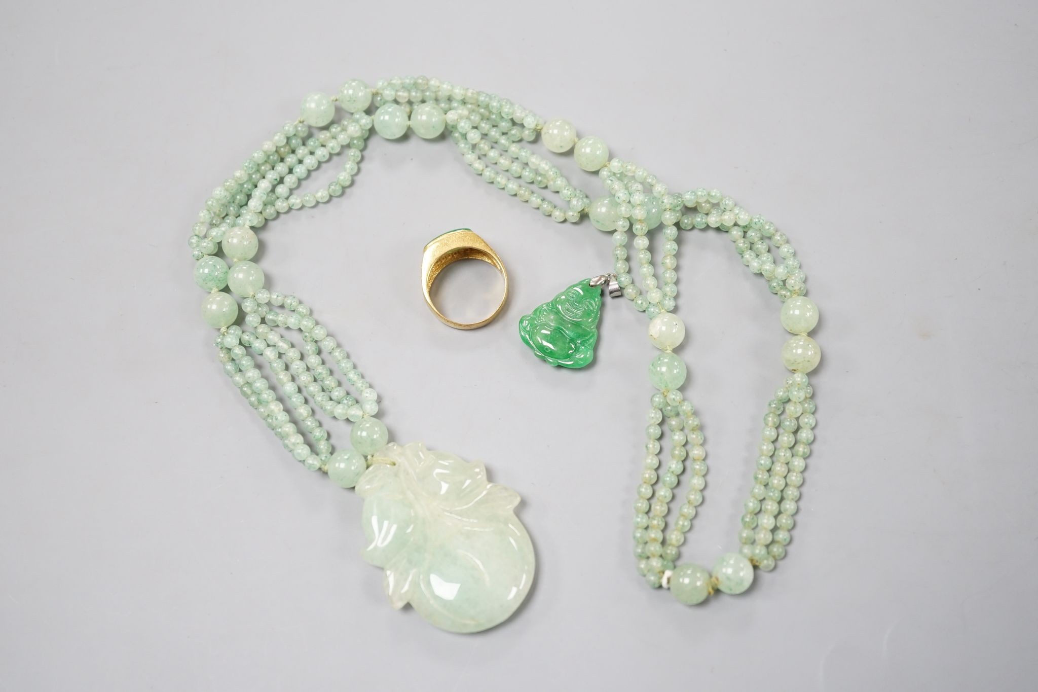 A carved jade pendant, 53mm on a quartz bead necklace, one other jade pendant and a jade, paste and gilt metal ring.